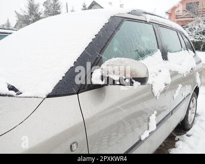 Schnee und Eis auf der Windschutzscheibe, den Rückspiegeln des Fahrzeugs. Winterliche Fahrbedingungen. Schneeräumen. Strassenverkehr im Winter. Metall Stockfoto