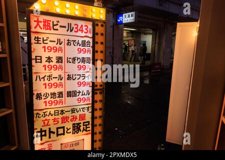 Osaka, Japan - 29. April 2023: Beleuchtetes Schild in japanischer Sprache mit Preisen für Barmahlzeiten im Restaurant nach Station Stockfoto