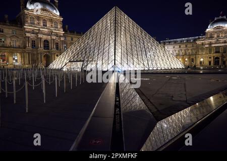 Die Louvre-Pyramide leuchtet nachts in einem leeren Innenhof Stockfoto