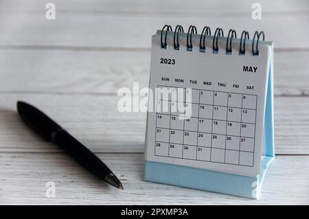 Mai 2023 weißer Tischkalender mit schwarzem Stift auf Holztisch. Kalenderkonzept Stockfoto