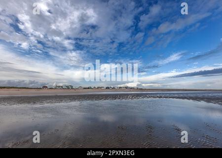 Strandhäuser in Dünen auf sonnigen, windigen Camber Sands in Rye Bay am English Channel, großer blauer Himmel und dramatische Wolken, Reflexion. Beliebt für Wassersportarten Stockfoto