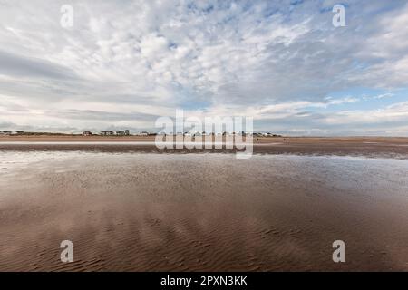 Große Himmelshäuser auf Dünen am sonnigen, windigen Camber Sands in Rye Bay am English Channel an der Grenze zu Sussex Kent und Wolkenformationen. Beliebt für Wassersportarten Stockfoto