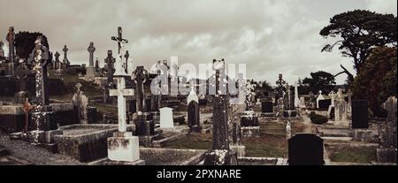 Ein Friedhof in Irland. Steingräber, keltisches Kreuz. Christlicher Friedhof, wolkiger Himmel Stockfoto