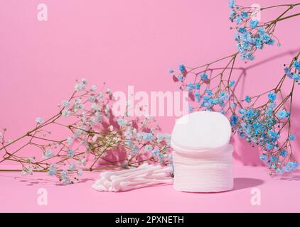 Runde kosmetische Polster aus Baumwolle und Wattestäbchen auf pinkfarbenem Hintergrund Stockfoto