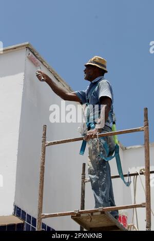 salvador, bahia, brasilien - 10. juli 2022: Wandmaler, der in einer öffentlichen Schule auf einem Gerüst eine Wand malt Stockfoto