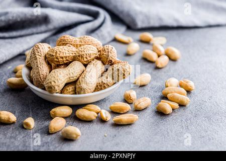 Ungeschälte und geschälte Erdnüsse auf dem Küchentisch. Stockfoto