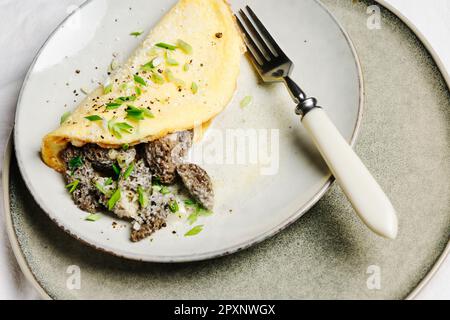 Omelette mit Morchelpilzen in einer cremigen Sauce mit Kräutern. Stockfoto