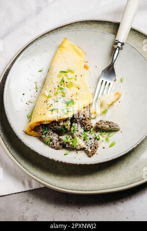 Omelette mit Morchelpilzen und Käse in einer cremigen Knoblauchsoße. Stockfoto