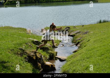 Ein Junge, der über einen Bach in Savoie springt Stockfoto