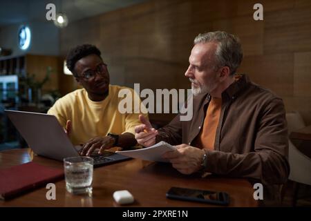 Kollegen, die planen, arbeiten mit einem Laptop zusammen, während sie ein Geschäftstreffen im Café abhalten Stockfoto