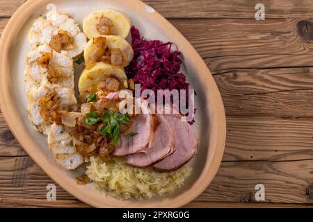 Geräuchertes Fleisch, serviert mit Rot- und Weißkohl und zwei Sorten Knödel Stockfoto