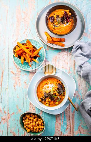 Karotten- und Süßkartoffelsuppe mit Kichererbsen und frischen Winterkräutern, Süßkartoffeln-Pommes Stockfoto