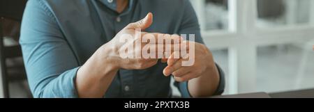Nahaufnahme eines Geschäftsmannes, der Gebärdensprache verwendet, während er mit dem im Büro sitzenden Kunden spricht Stockfoto