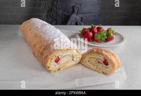 Puderzucker über ein frisch gebackenes schweizer Brötchen streuen Stockfoto