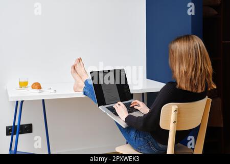 Unbekannte Frau, die das Bewerbungsformular ausfüllt, sitzt in der Mietwohnung. Stellensuche online Konzept. Stockfoto