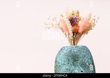 Strauß getrockneter Blumen und Stacheln in Keramikvase auf rosa Hintergrund mit Kopierraum Stockfoto