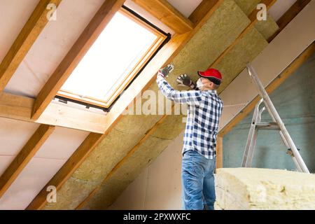 Installation von Dämmstoffen im Dachboden für die Hausrenovierung. Ökologisches Heimkonzept. Stockfoto