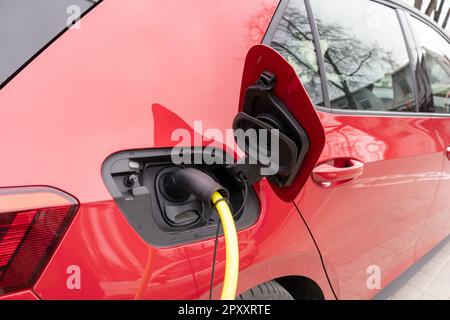 Ein rotes Auto mit schwarzem Dach und einem gelben Stromkabel. Stockfoto