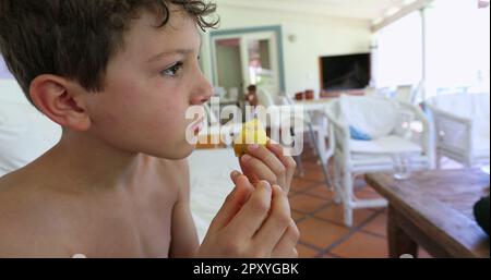 Hübscher Junge, der Obst isst. Kind isst gesunden Pfirsich-Snack Stockfoto