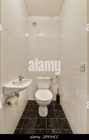 Ein kleines Bad mit schwarz-weißen Fliesen auf dem Boden, Waschbecken und Toilette in der Wand ist aus Marmor Stockfoto