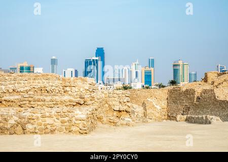 Ruinen der portugiesischen Festung Qalat al-Bahrain mit der Innenstadt im Hintergrund, Manama, Bahrain Stockfoto