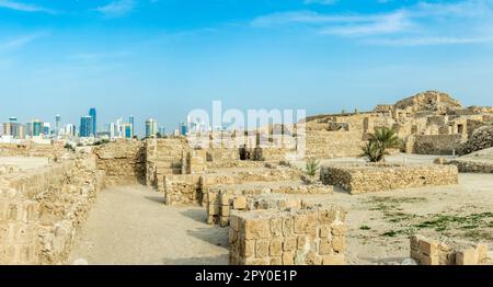 Ruinen der portugiesischen Festung Qalat al-Bahrain mit der Innenstadt im Hintergrund, Manama, Bahrain Stockfoto