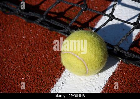 Tennisszene mit schwarzem Netz und Ball auf weißer Linie in der Low-Angle-Ansicht und selektivem Fokus Stockfoto