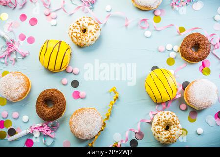 Deutsche Krapfen oder Donuts mit Bändern und Konfetti. Traditioneller Berliner für Karneval und Party. Farbenfrohes Karneval- oder Geburtstagsbild Stockfoto