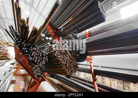 Dünne Metallstäbe stapeln sich auf einem großen Regal im Kühllager Stockfoto