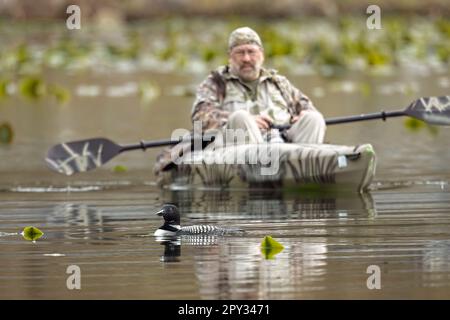 Ein Editorial-Foto eines Fotografen in einem Kajak, der auf dem Fernan Lake in Nord-Idaho einen Wasserflugzeug fliegt. Stockfoto