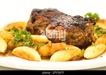 Köstliche Hausmannskost: Fleischbällchen mit Kartoffelnudeln und Petersilie in herzhafter Soße Stockfoto