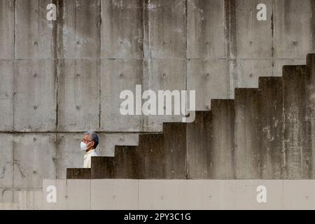 Ein Japaner, der eine chirurgische Gesichtsmaske trägt, steigt einige Treppen in Kawasaki, Kanagawa, Japan hinab. Stockfoto