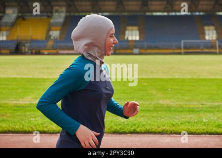 Eine muslimische Frau in einer Burka sportlich muslimische Kleidung, die auf einem Marathonkurs läuft und sich auf die nächsten Wettkämpfe vorbereitet Stockfoto