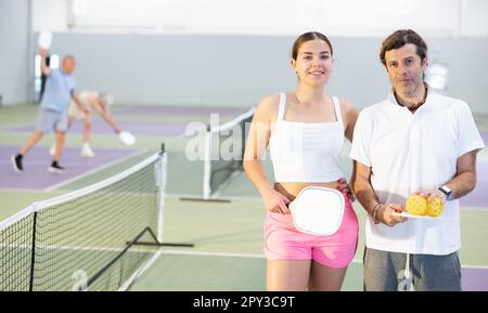 Junge Mädchen und Erwachsene, Pickleball-Spieler, die auf dem Platz stehen Stockfoto