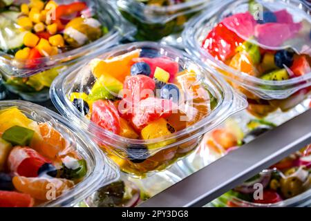 Plastikboxen mit vorverpackten Obstsalaten, in einem handelsüblichen Kühlschrank zum Verkauf aufgemacht Stockfoto