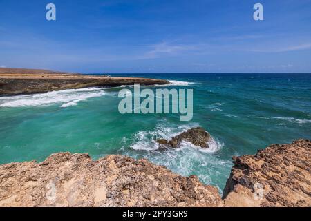 Wunderschöne felsige Küste und endloses türkisfarbenes Wasser des Atlantischen Ozeans, das sich mit blauem Himmel am Horizont verschmilzt. Stockfoto