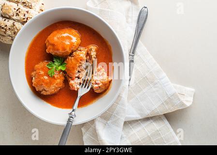 Gebratene Fleischbällchen, geschmort in Tomatensauce, serviert auf einem weißen Tisch. Ich esse mit Rind gebratene Fleischbällchen in Tomatensoße. Stockfoto
