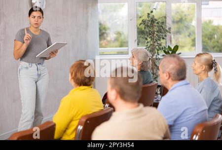 Ein junges Mädchen, das einer Gruppe älterer Erwachsener einen Vortrag hält Stockfoto