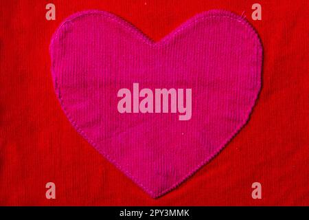 Nahaufnahme eines großen rosa Herzens auf rotem Stoffhintergrund. Valentinstag- oder Muttertagkonzept. Speicherplatz kopieren. Stockfoto