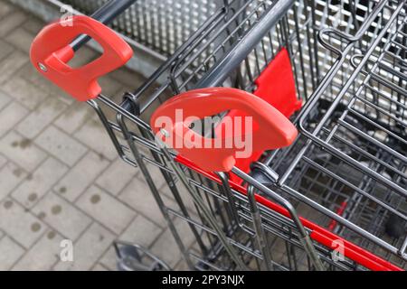 Griffe von Einkaufswagen in Nahaufnahme vor einem Supermarkt Stockfoto