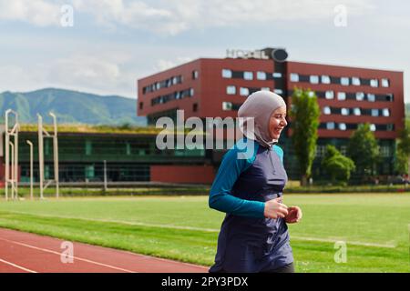 Eine muslimische Frau in einer Burka sportlich muslimische Kleidung, die auf einem Marathonkurs läuft und sich auf die nächsten Wettkämpfe vorbereitet Stockfoto