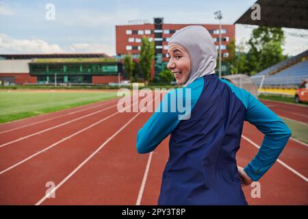 Eine muslimische Frau in einer Burka sportlich muslimische Kleidung, die auf einem Marathonkurs läuft und sich auf die nächsten Wettkämpfe vorbereitet Stockfoto