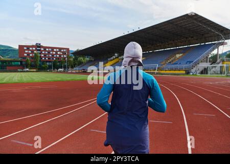 Eine muslimische Frau in einer Burka sportlich muslimische Kleidung, die auf einem Marathonkurs läuft und sich auf die nächsten Wettkämpfe vorbereitet Stockfoto