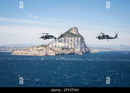 Straße Von Gibraltar. 12. April 2023. Ein MH-60s Nighthawk Hubschrauber, der an Helicopter Sea Combat Squadron (HSC) 5 befestigt ist, und ein MH-60R Sea Hawk Hubschrauber, angeschlossen an Helicopter Maritime Strike Squadron (HSM) 46, fliegen in Formation, während sie die Straße von Gibraltar durchqueren, 12. April 2023. Carrier Air Wing (CVW) 7 ist die offensive Luft- und Streikkomponente der Carrier Strike Group (CSG) 10 und der George H.W. Buchse CSG. Die Geschwader von CVW-7 sind Strike Fighter Squadron (VFA) 143, VFA-103, VFA-86, VFA-136, Carrier Airborne Early Warning Squadron (VAW) 121, Electronic Attack Squadron (VAQ) 140, HS Stockfoto