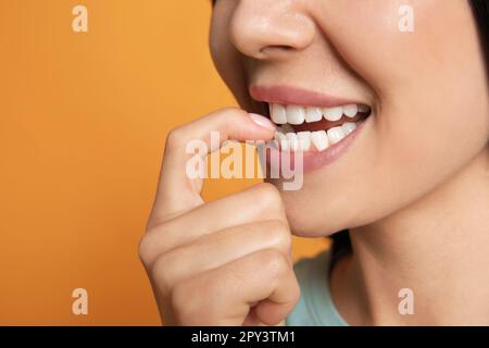 Eine junge Frau, die sich auf gelbem Hintergrund die Nägel biss, Nahaufnahme Stockfoto