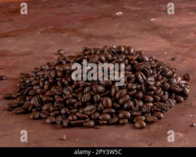 Kleiner Haufen Kaffeebohnen, isoliert auf handbemaltem braunem Hintergrund. Stockfoto