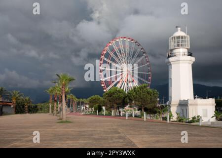 Verschwommener Blick auf das Riesenrad und den Leuchtturm unter regnerischen Wolken Stockfoto