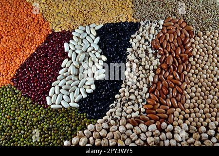 Verschiedene Rohleguminosen mit verschiedenen Farben und Texturen. Verteilen Sie den Rahmen auf dem Tisch. Stockfoto
