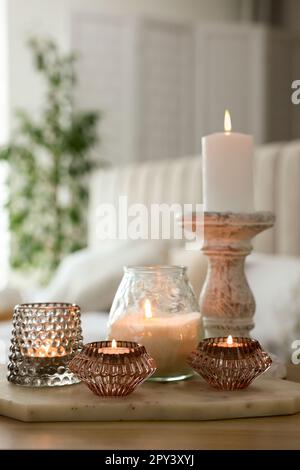 Set aus Duftkerzen und Kerzenhalter auf Holztisch im Zimmer Stockfoto