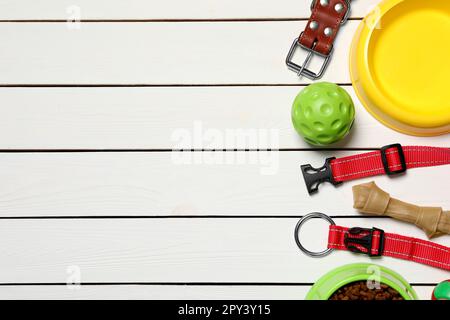 Flach liegend mit Hundehalsband, Spielzeug und Schüssel auf weißem Holztisch. Platz für Text Stockfoto